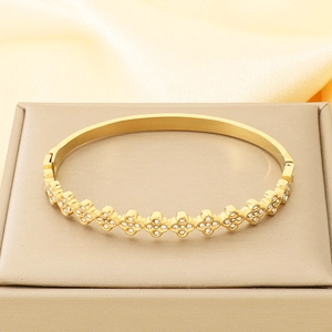 Detailed close-up of golden cross flower bangle inlaid with white sparkling zircon stones