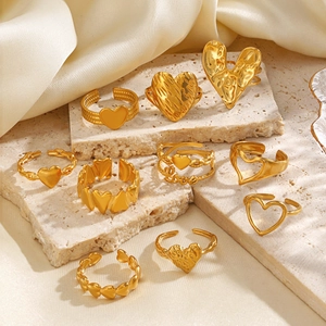 Set verstellbarer goldener Herzringe in verschiedenen Designs auf Marmorhintergrund