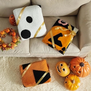 Detail of neatly folded Halloween ghost flannel blankets tied with elegant gold ribbons