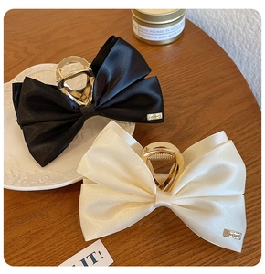 Detailed view of elegant black and beige bow hair claws with gold-finished metal clips