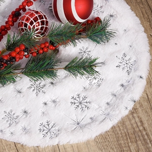 Mini white plush Christmas tree skirt with silver snowflake pattern on wooden floor