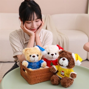 Three Christmas teddy bears in a basket wearing festive hats and Merry Christmas shirts