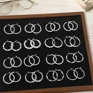 Macro view of 16 silver hoop earring sets with varied textures on black display