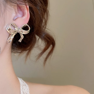 Gros plan de boucles d'oreilles nœud argentées portées sur un mannequin au fini métal