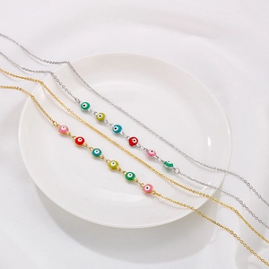 Multi-colored evil eye charms on layered gold and silver chains shown on white ceramic plate