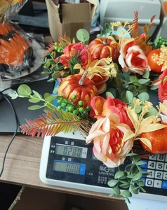 Detail view of fall pumpkin and rose wreath weighing 0.280kg on an electronic scale
