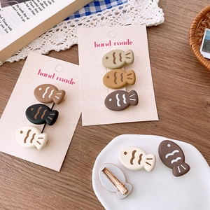 Set of cute cartoon fish-shaped hair clips in beige and brown with golden metal duckbill base