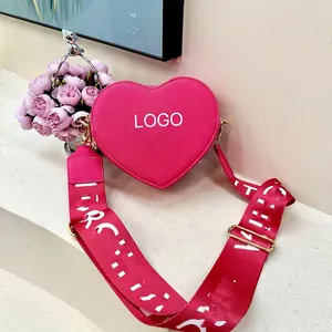 Fuchsia heart-shaped crossbody bag with textured leather and wide graphic strap