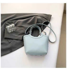 Detail of mint blue leather bucket bag with fine texture on gray suit jacket background