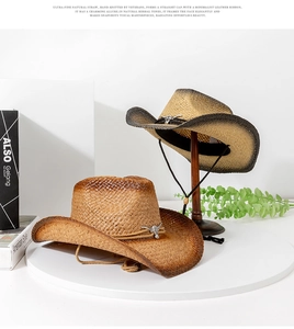 Detail of woven straw cowboy hat featuring metal bull pendant and leather cord trim