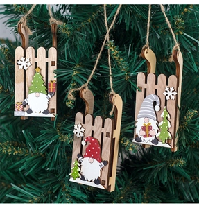 Three creative wooden Christmas gnome sled ornaments hanging on a festive tree branch