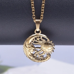 Detailed close-up of sun and moon pendant on a golden chain against black leather