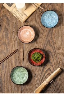 Dettaglio di quattro ciotole per salse in ceramica colorata su un tavolo in legno