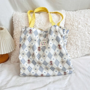 Detail of blue quilted canvas tote bag featuring cute bear prints and yellow straps
