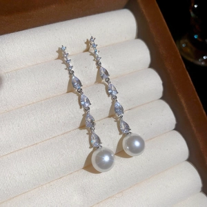 Close-up of elegant silver drop earrings with shimmering zircon and white pearls