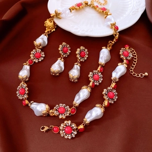 Details des Vintage-Schmucksets mit Barockperlen und roten Kristallblüten auf braunem Stoff