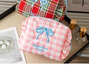 Detailed close-up of plaid cosmetic bags with blue bows and ruffled edges in a lifestyle set