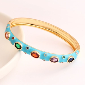 Golden bracelet with sky blue enamel and colorful cubic zirconia on white ceramic