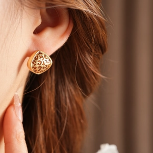 Gros plan de boucles d'oreilles léopard dorées irrégulières portées par un modèle