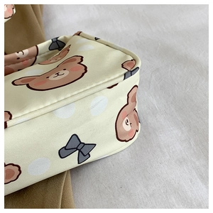 Close-up of beige canvas shoulder bag with cute cartoon bear and grey bow patterns