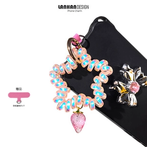 Detailed view of iridescent star-shaped spiral cord with strawberry charm on a phone case