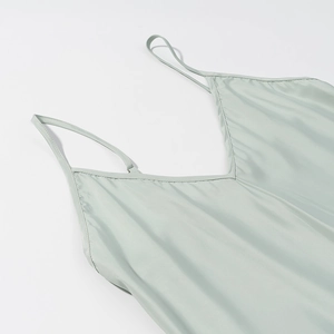 Close-up of V-neck stitching and silk texture on light green pleated satin dress