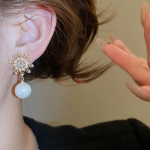Close-up of elegant snowflake pearl drop earrings with sparkling zircon stones in gold