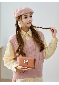 Close-up of caramel long wallet with butterfly buckle and zip closure held by model