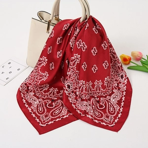 Rotes Satin-Halstuch mit Paisley-Muster an einer weißen Handtasche als Accessoire