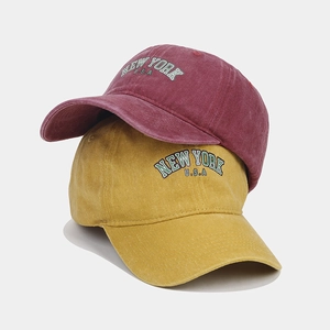 Close-up of New York embroidery on burgundy and mustard washed cotton baseball caps