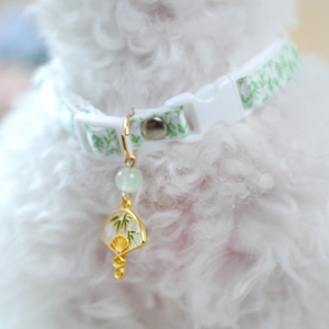 Detail of pet collar with bamboo leaf patterns and a golden fan-shaped pendant charm
