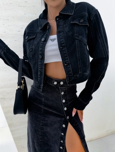 Détail d'une jupe en jean avec fente à boutons et veste assortie en jean noir délavé