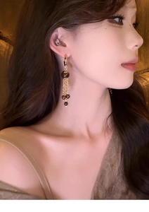 Detailed side view of vintage tassel earrings with dark beads and gold chains on a model