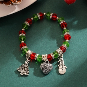 Gros plan du bracelet de Noël avec perles de cristal rouges, vertes et breloques de fêtes