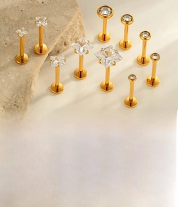 Detail of G23 titanium labret studs with square and round zircons in gold finish