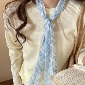 Close-up detail of a light blue plaid mesh scarf necklace styled with a yellow knit top