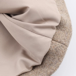 Detailaufnahme des braunen Tweed-Mantels mit glattem beige Innenfutter und präzisen Nähten