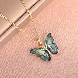 Detailed macro of gold chain necklace featuring a blue sparkling butterfly pendant