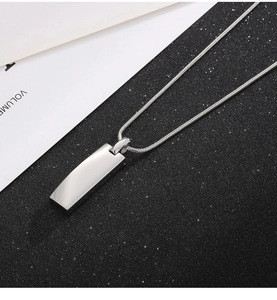 Detailed view of silver rectangular pendant with a sleek snake chain on a contrast backdrop