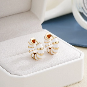 Detailed close-up of retro gold and white enamel hoop earrings in a jewelry box
