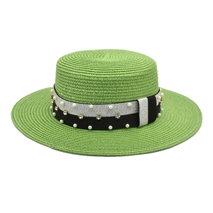 Detail of green straw boater hat with pearl and rhinestone embellishments on a woven band