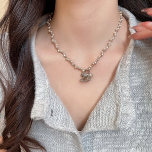 Macro detail of silver rocking horse pendant with zircons and pearls on necklace