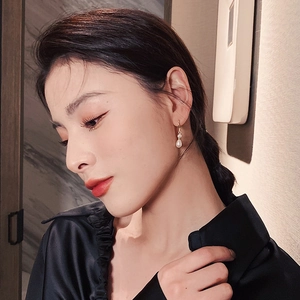 French baroque pearl drop earrings in gold shown on a model for a stylish look