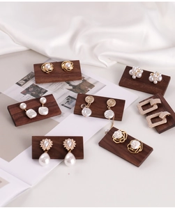 Assorted vintage earring set displayed on walnut wood stands with satin backdrop