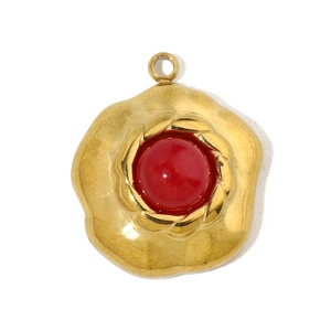 Detailed close-up of a vintage gold floral pendant with a central red stone inlay
