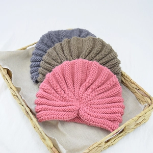 Detailed knit texture of pink, grey, and khaki bohemian beanies in a woven basket