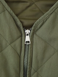 Macro shot of metal zipper detail and diamond quilted texture on olive green jacket