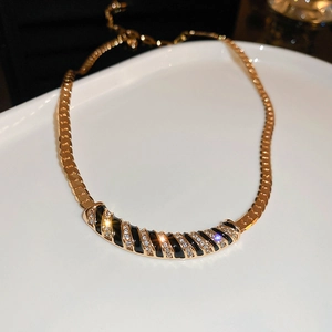 Close-up of gold chain necklace with black enamel stripes and shimmering inlaid diamonds