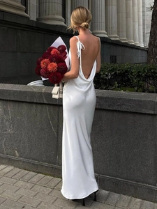 Détail de robe en satin blanc avec dos nu orné d'une chaîne dorée et nœuds d'épaule