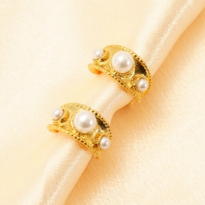 Gold C-shaped pearl hoop earrings with beaded edges on a soft silk background